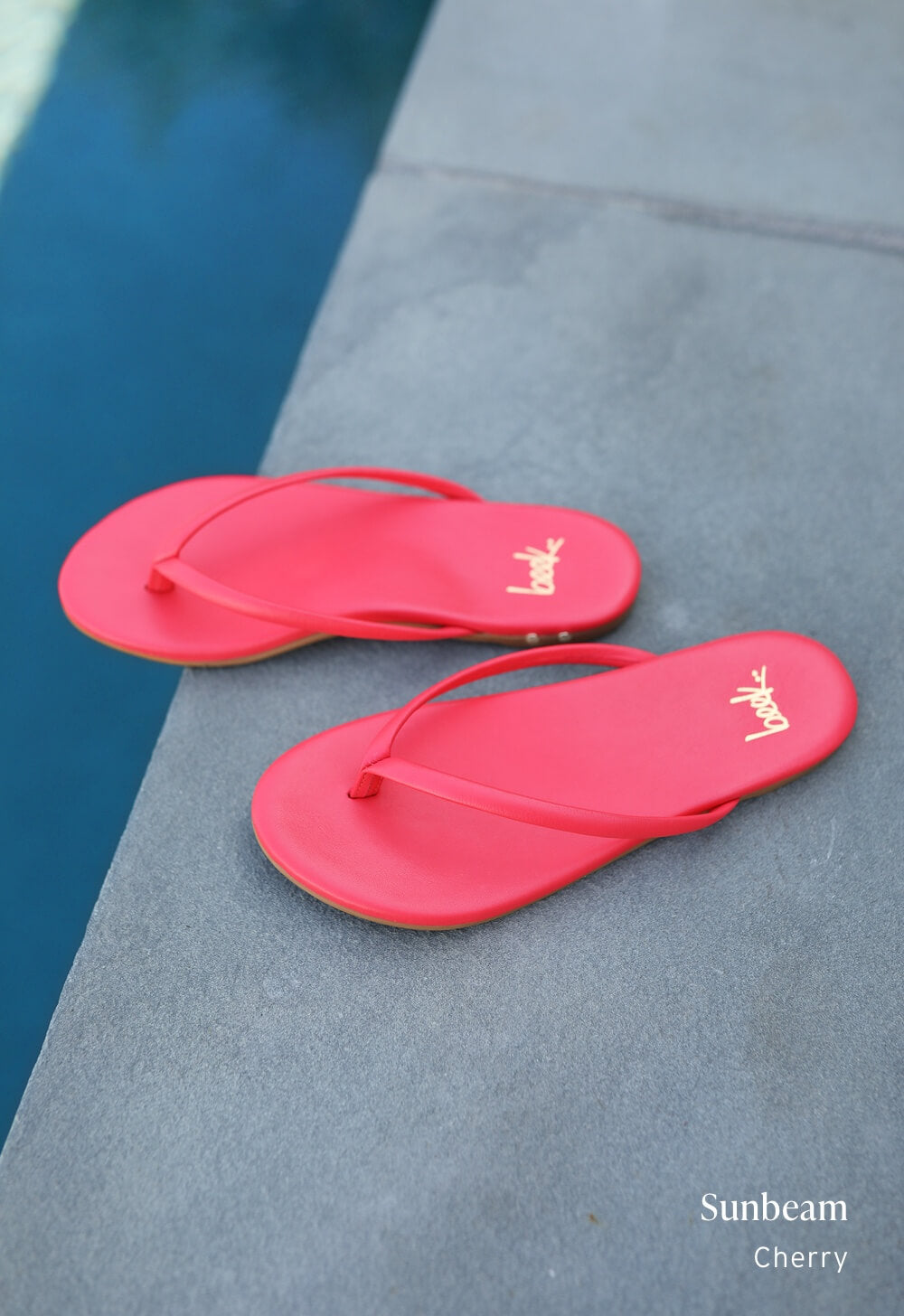 Sunbeam leather flip flop sandals in cherry next to pool