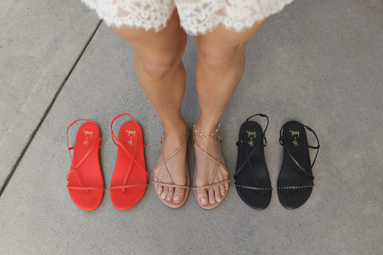 Shannon wearing Bitsybird leather sandal in beach standing next to the Bitsybird in tomato and black