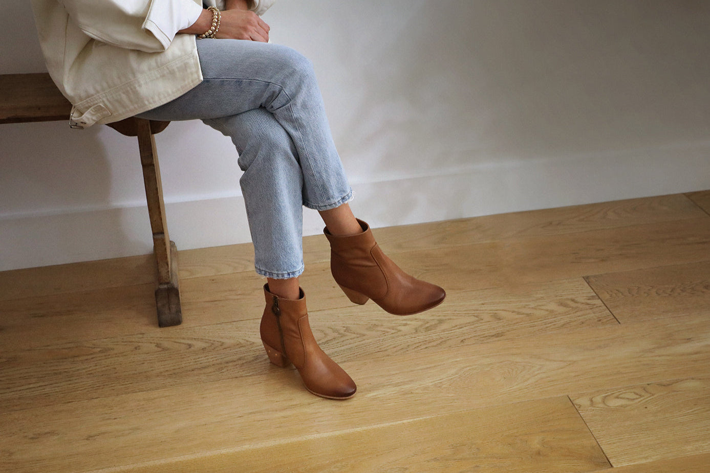 Woman wearing Catbird leather boots in tan with jeans and cream jacket