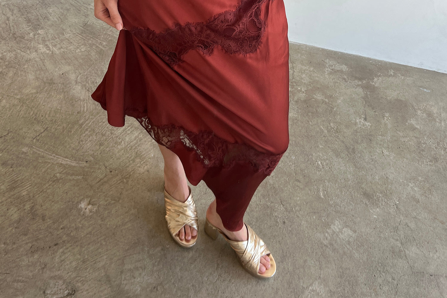 Woman wearing Chachabird leather heeled sandals in gold with red holiday satin dress