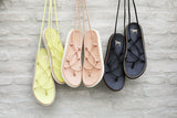 Chirp leather ankle wrap sandals in citrus, beach, and black hanging on the wall