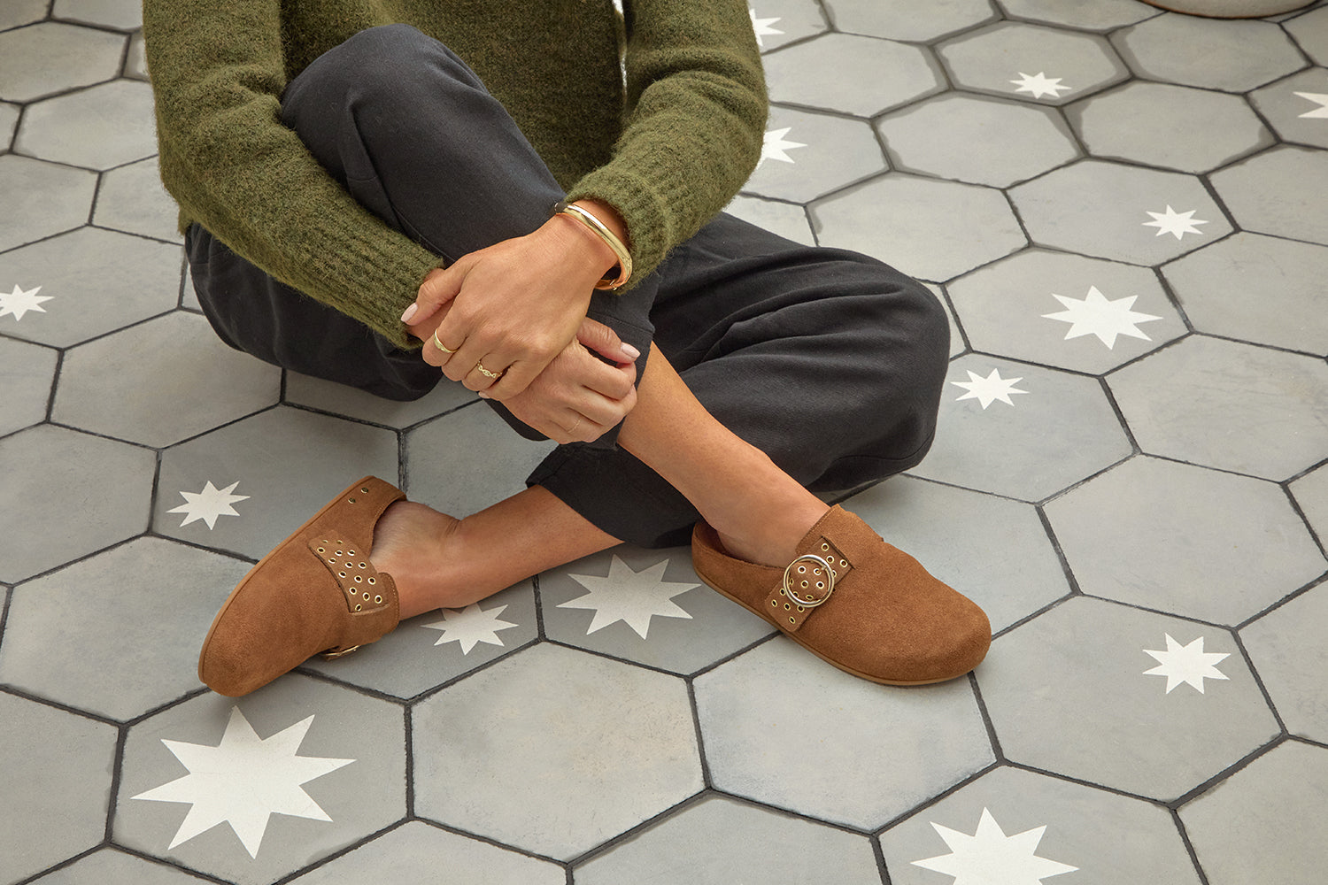Woman wearing Comet suede mule in chestnut with gray pants and green sweater.