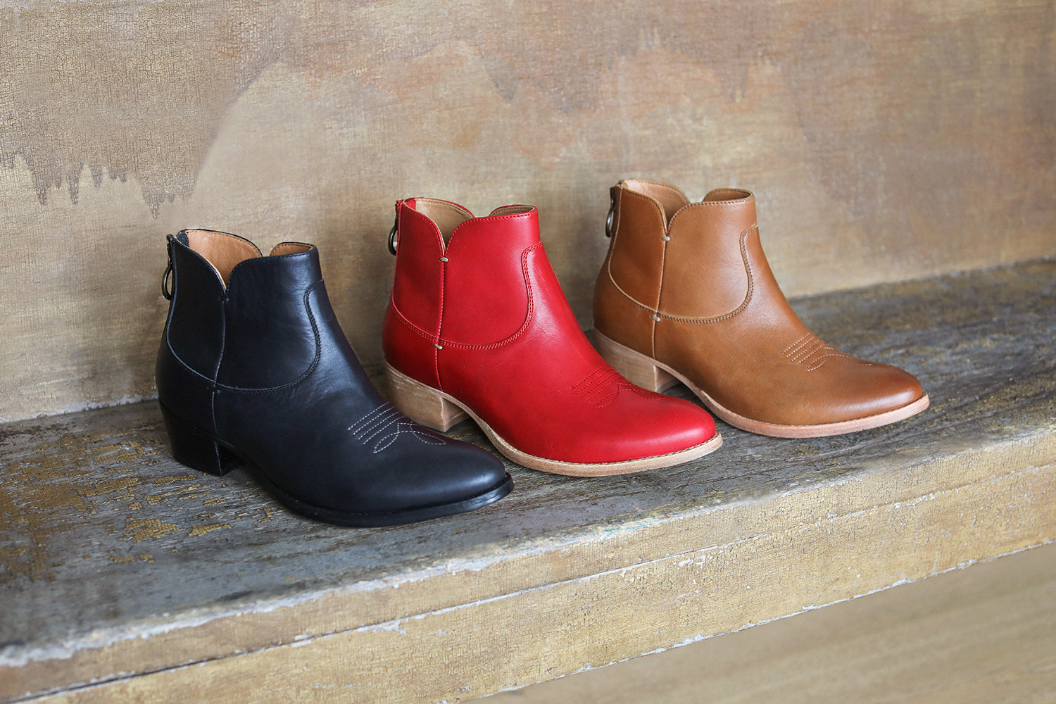 Group shot of Cowbird leather ankle boots in black, red, and tan