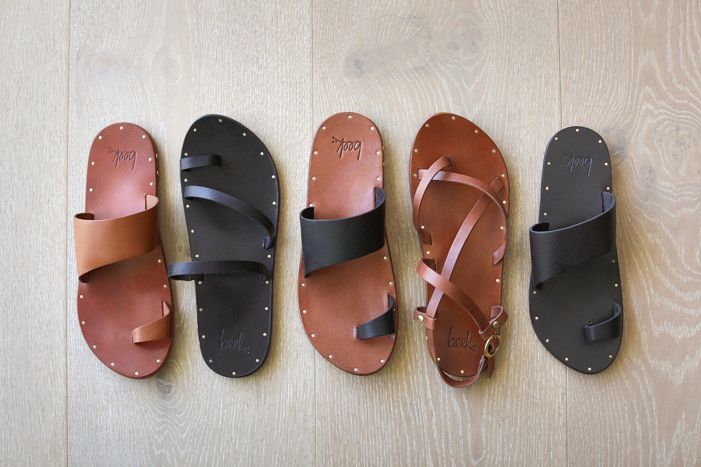 Group shot of Finch leather toe-ring sandal in tan, black/tan, and black with Nene leather sandal in blsck and Linnet leather sandal in tan.