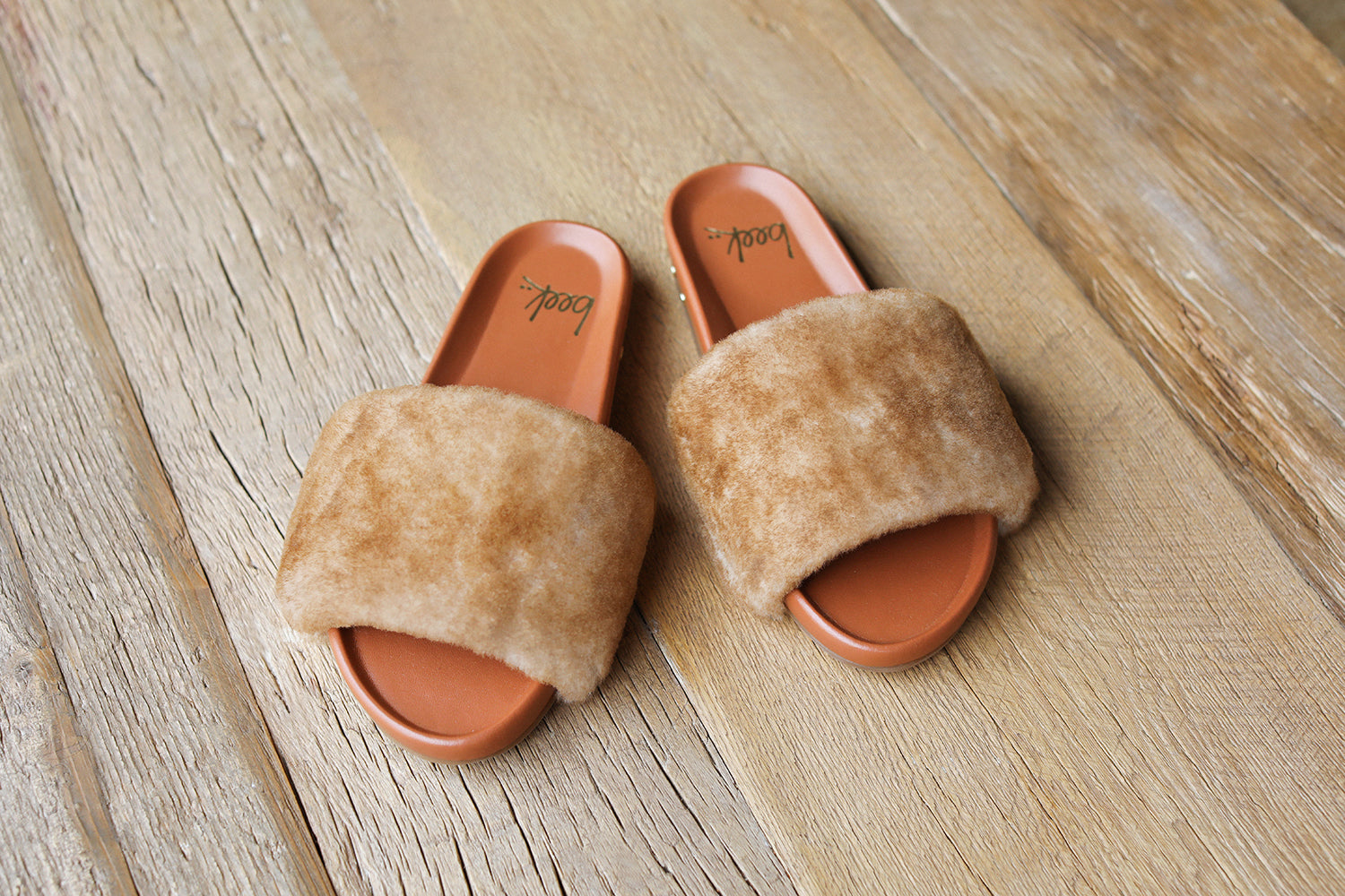 Gallito Más Shearling slide sandals in honey/tan on wooden floor