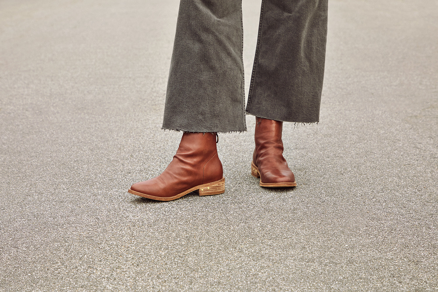 Woman wearing Hawk leather ankle boot in mahogany with gray pants