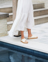Woman wearing Hen leather platform criss-cross sandals in eggshell with white dress