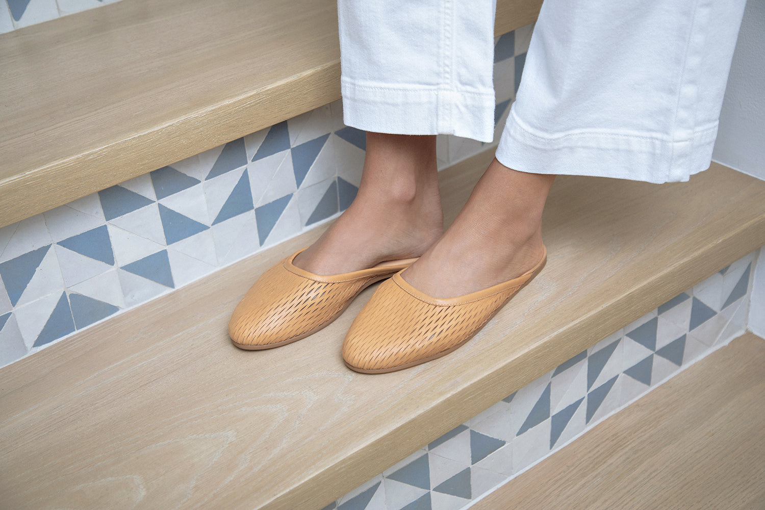 Woman wearing Phoebe Perforated leather ballet mule in honey with white pants