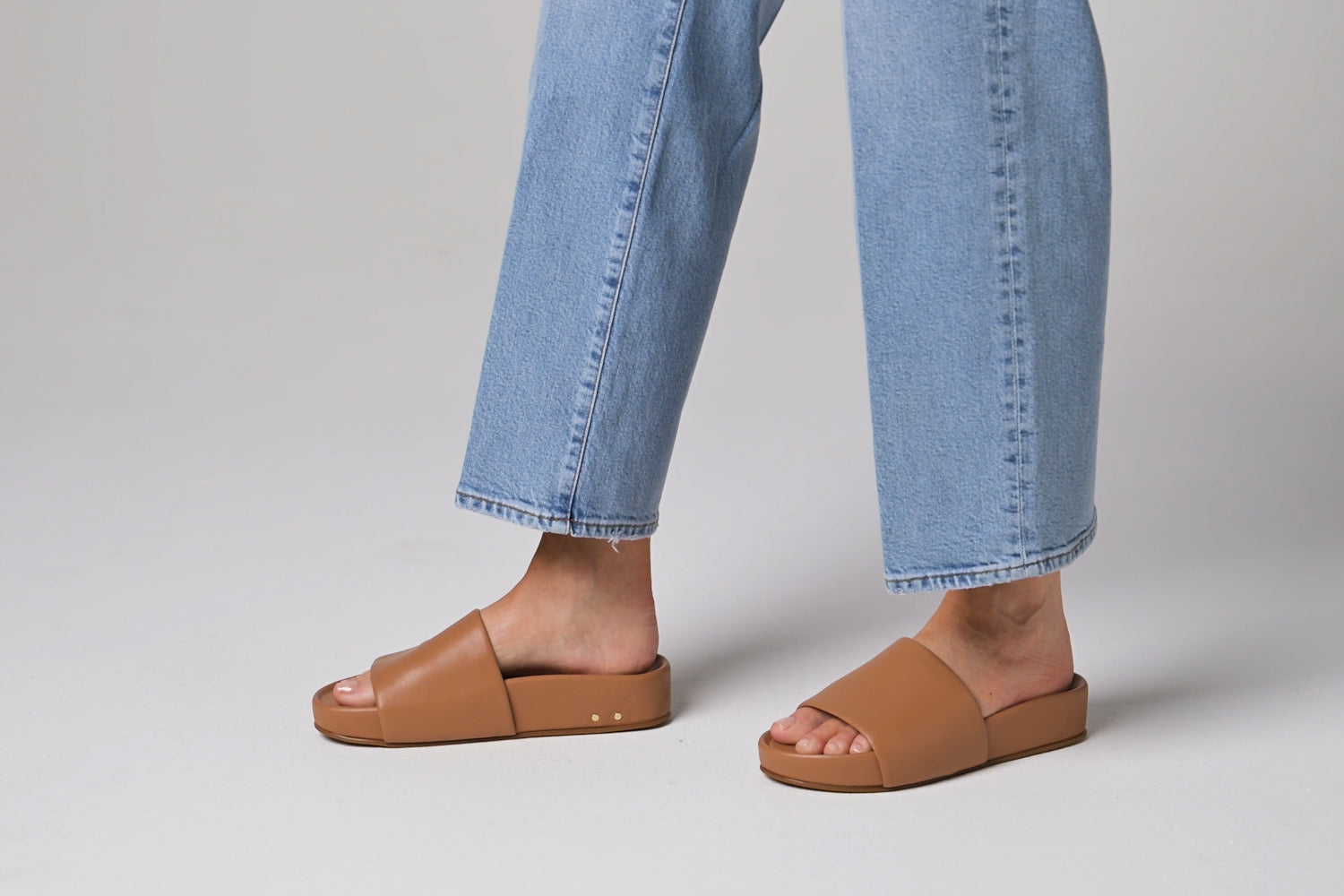 Video of woman walking in Pelican leather slide sandals in honey with jeans
