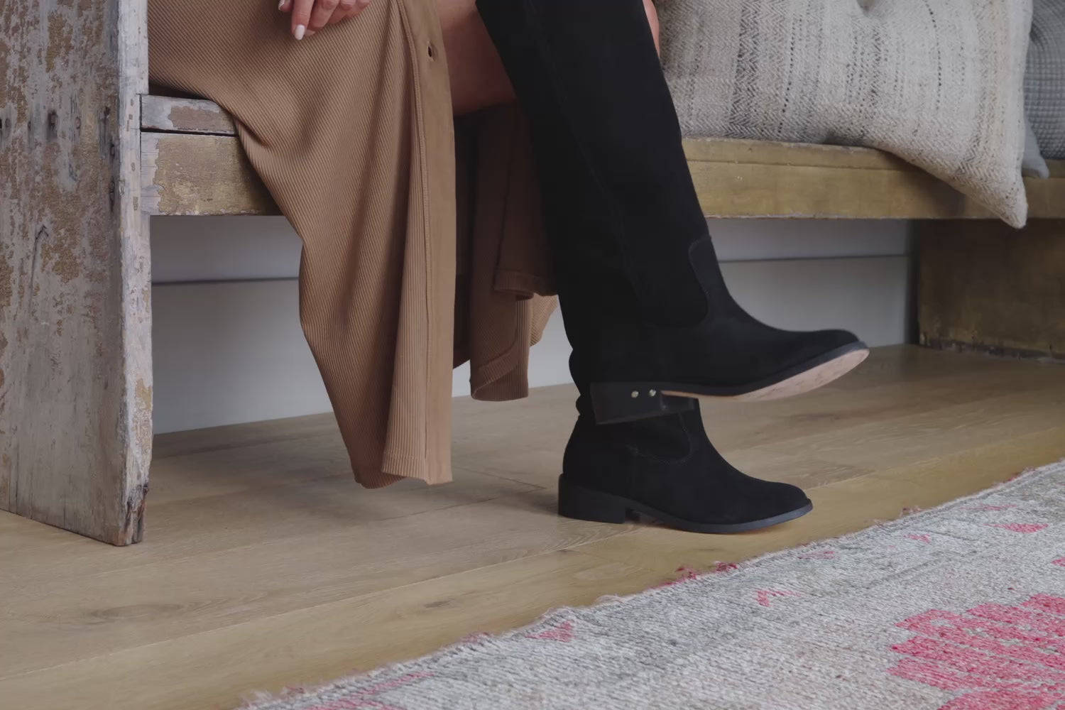 Video of woman wearing Nuthatch suede knee-high boot in black with tan shirt dress, sitting on bench and walking.