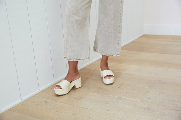 Woman wearing Prinia leather platform heel sandal in eggshell with light gray jeans
