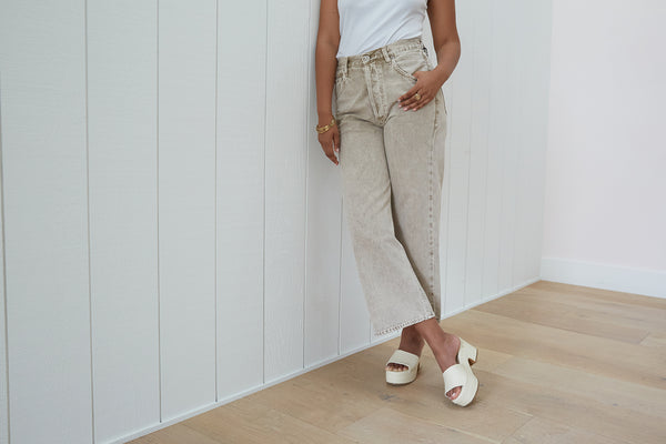 Woman wearing Prinia leather platform heel sandal in eggshell with light gray jeans