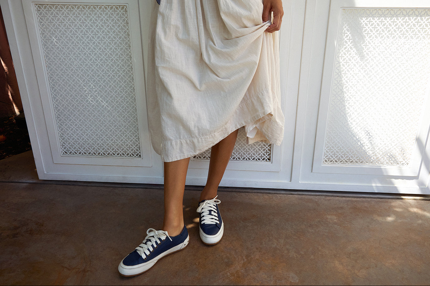 Woman wearing Sandpiper leather sneaker in navy with white dress