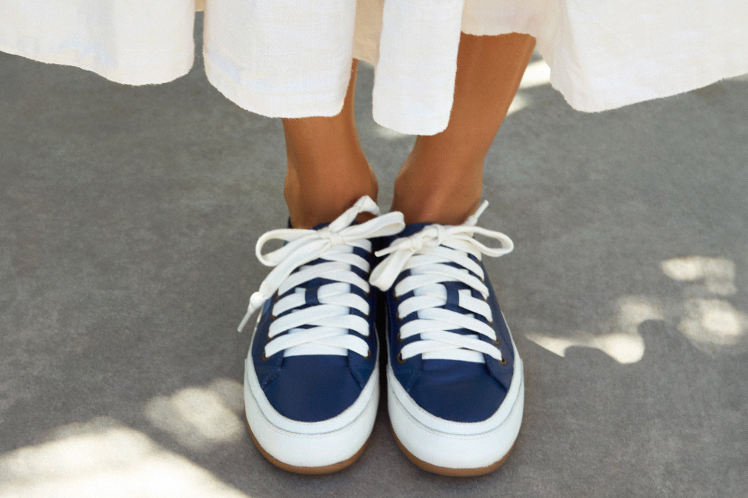 Woman wearing Sandpiper leather sneaker in navy with white dress
