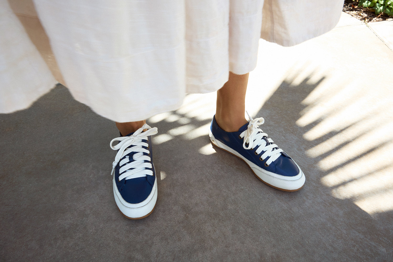 Woman wearing Sandpiper leather sneaker in navy with white dress