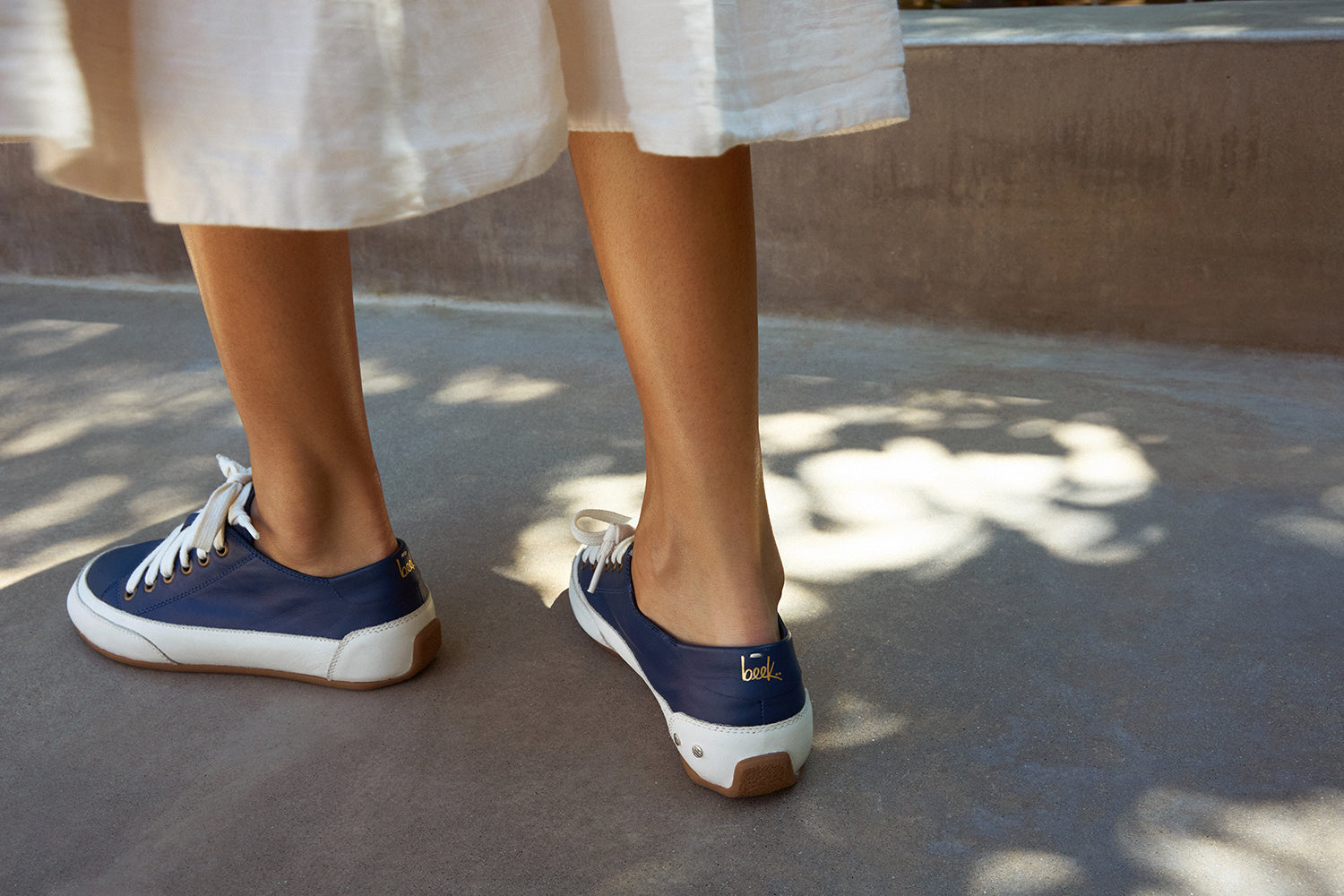 Woman wearing Sandpiper leather sneaker in navy with white dress
