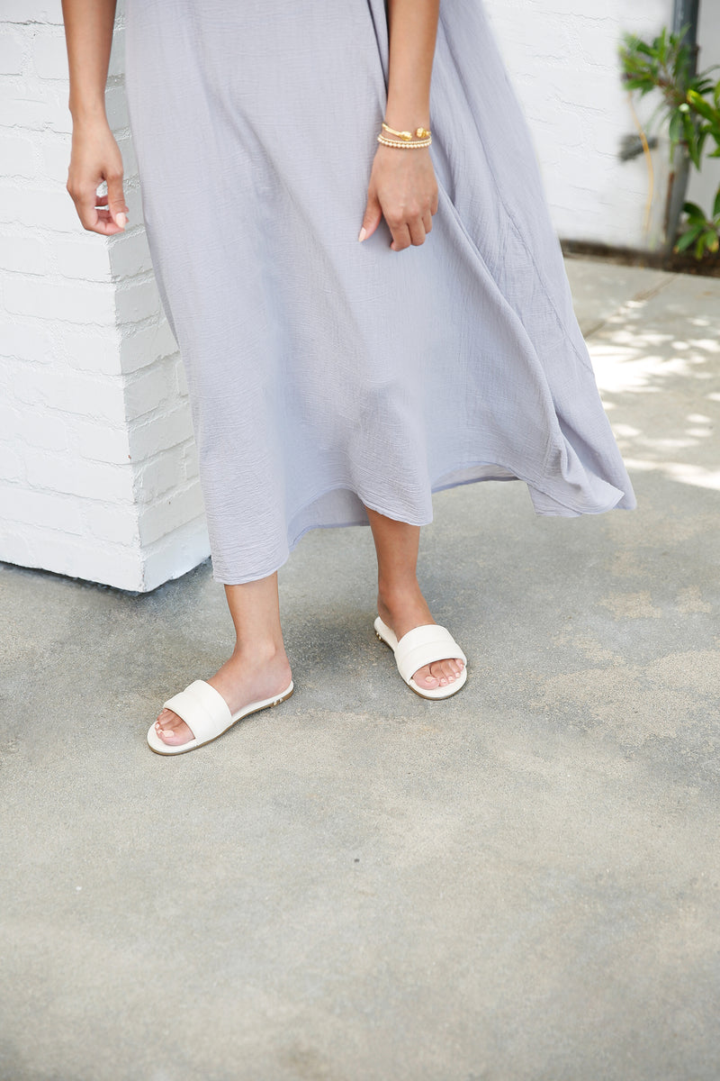 Woman wearing Sugarbird slide sandals in eggshell with gray dress