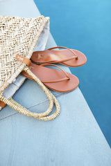 Sunbeam leather flip flop sandal in tan in woven bag by the pool.