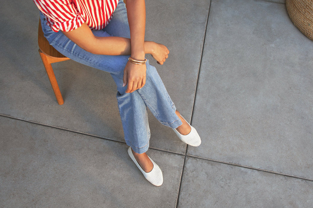 Woman wearing Swiftlet Perforated leather ballet slipper in vanilla with jeans and striped red shirt