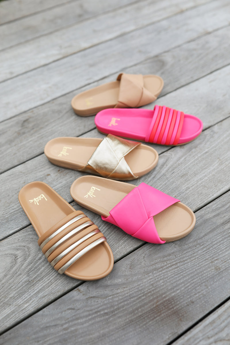 Group shot of Woman wearing Hoopoe leather slide sandals in gold/honey and cherry/azalea with Tori leather slide sandals in azalea/beach, gold/beach, and beach.