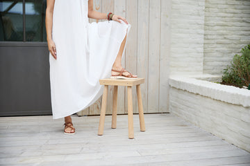 Woman wearing Wigeon burnished leather toe-ring sandal in cognac with white dress