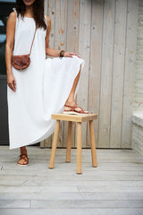 Woman wearing Wigeon burnished leather toe-ring sandal in cognac with white dress