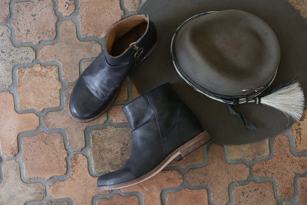 Product shot of Quail black leather boots and a hat