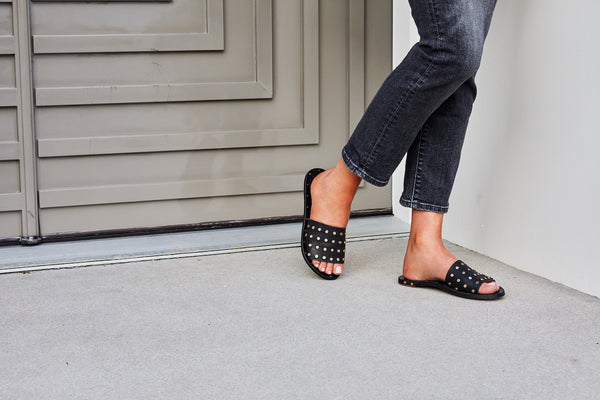 Woman wearing Lovebird Stud slide sandals in black