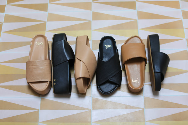 Group shot of Albatross slide sandal in beach and black, Oriole slide sandal in beach and black, Pelican slide sandals in honey and black. 