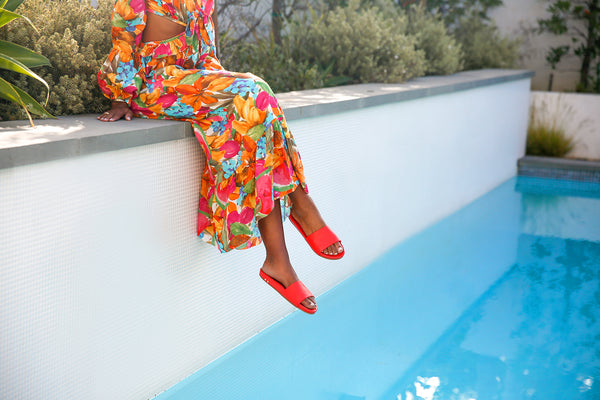 Woman in floral dress wearing Gallito leather slide sandals in poppy.