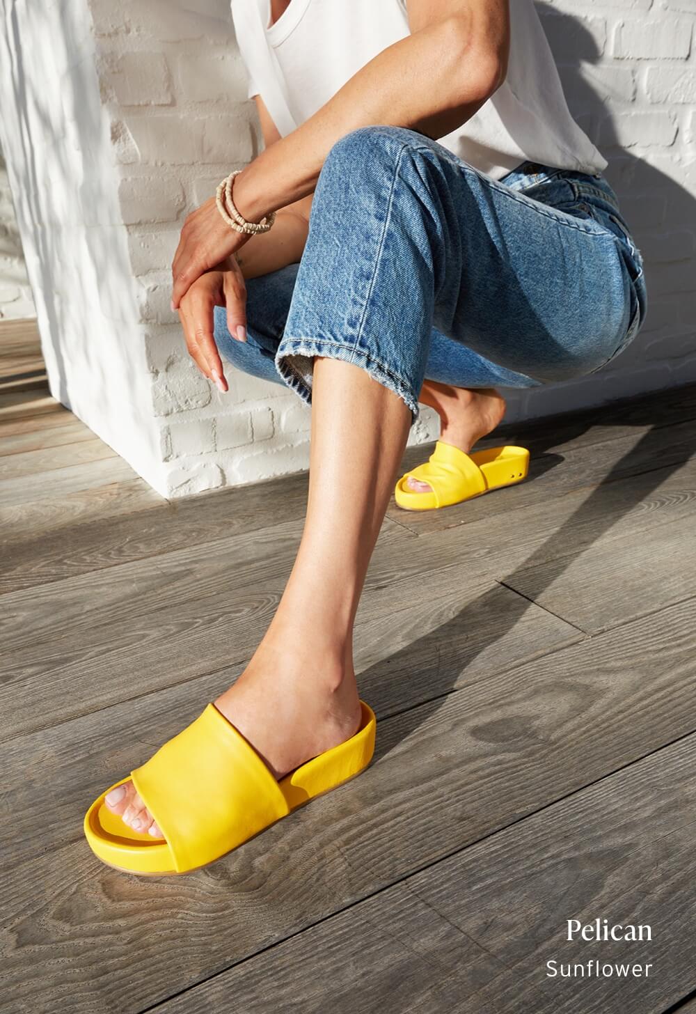 Woman wearing Pelican platform sandals in sunflower with jeans.