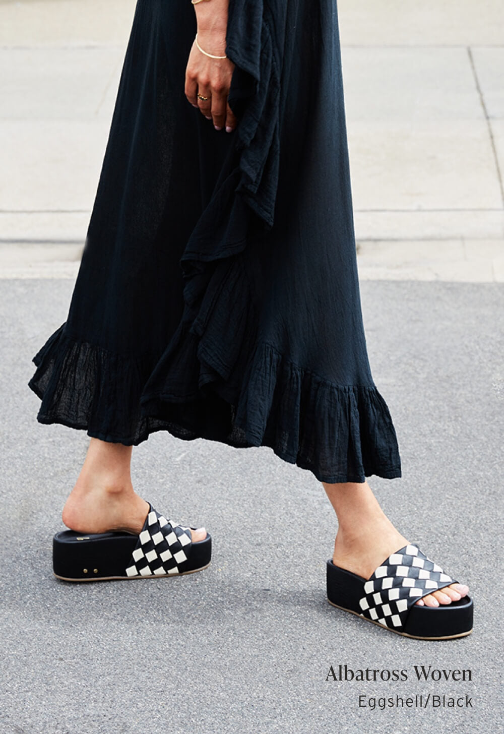 Woman wearing Albatross Woven leather platform sandals in eggshell/black with black dress.