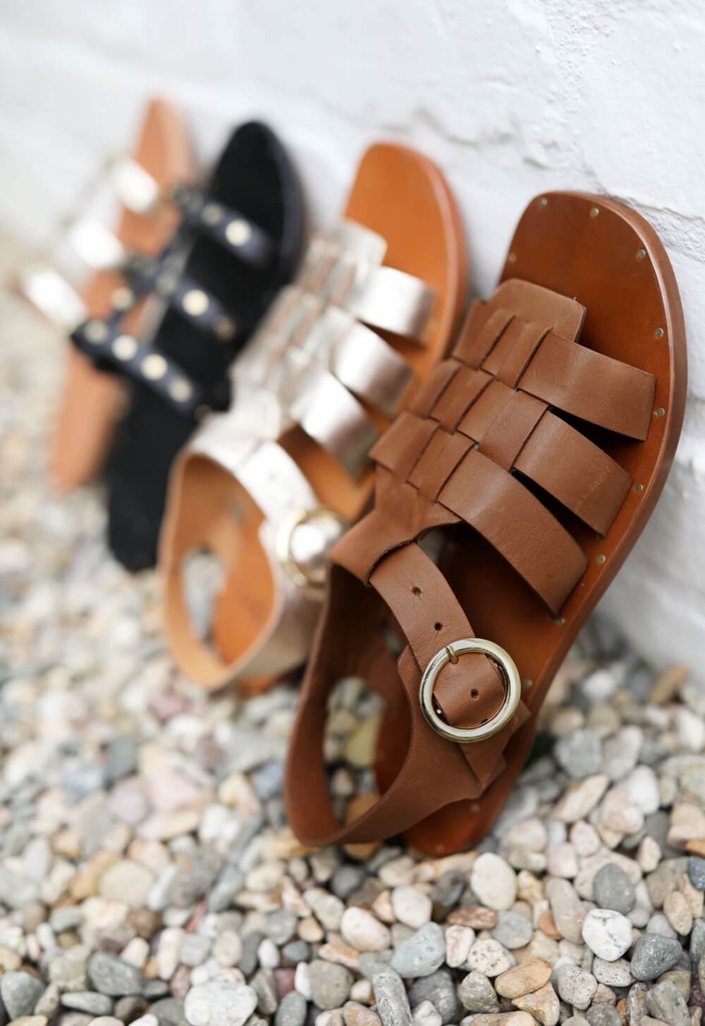 Group shot of Starfisher leather sandals in cognac and gold/honey with I'iwi leather sandals in black and gold/honey