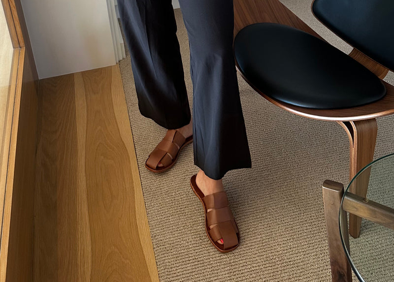 Alicia from @lifestyle_wifestyle wearing Broadbill leather mules in cognac with black slacks and vest..