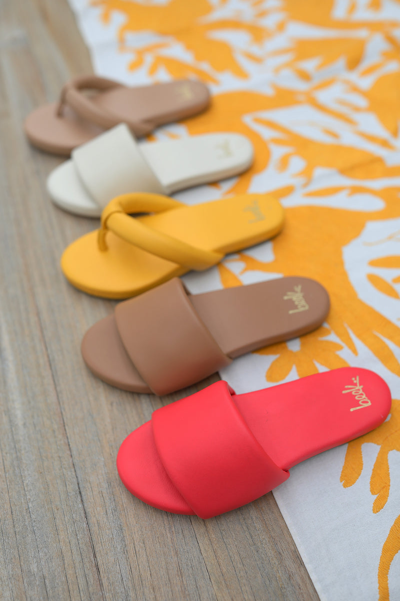 Group shot of Ruby leather thong sandals in beach and sunflower and Baza leather slide sandals in eggshell, honey, cherry.