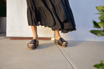 Woman wearing Albatross Textile leather platform sandals in black with black dress