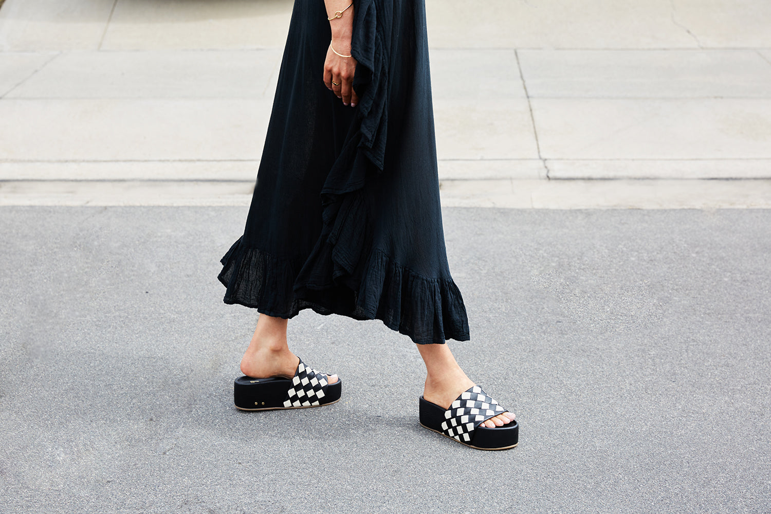Woman wearing Albatross Woven leather platform sandals in eggshell/black with black dress.