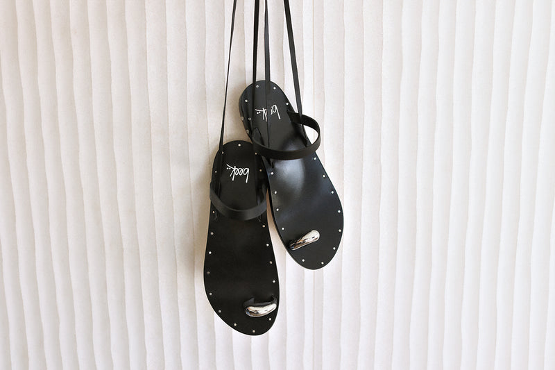 Amethyst Leather toe-ring ankle wrap sandal in black hanging on wall