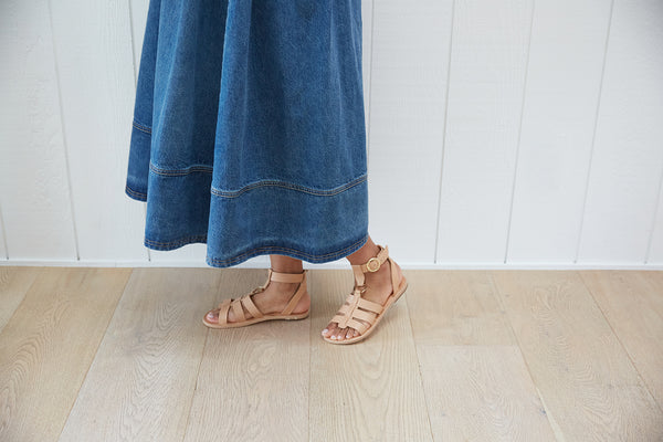 Woman wearing Attila ankle strap leather sandals in beach with denim skirt.