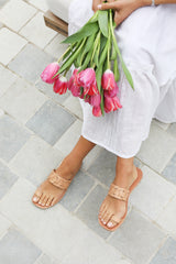 Woman wearing Barbet leather toe-ring sandals in honey with white dress