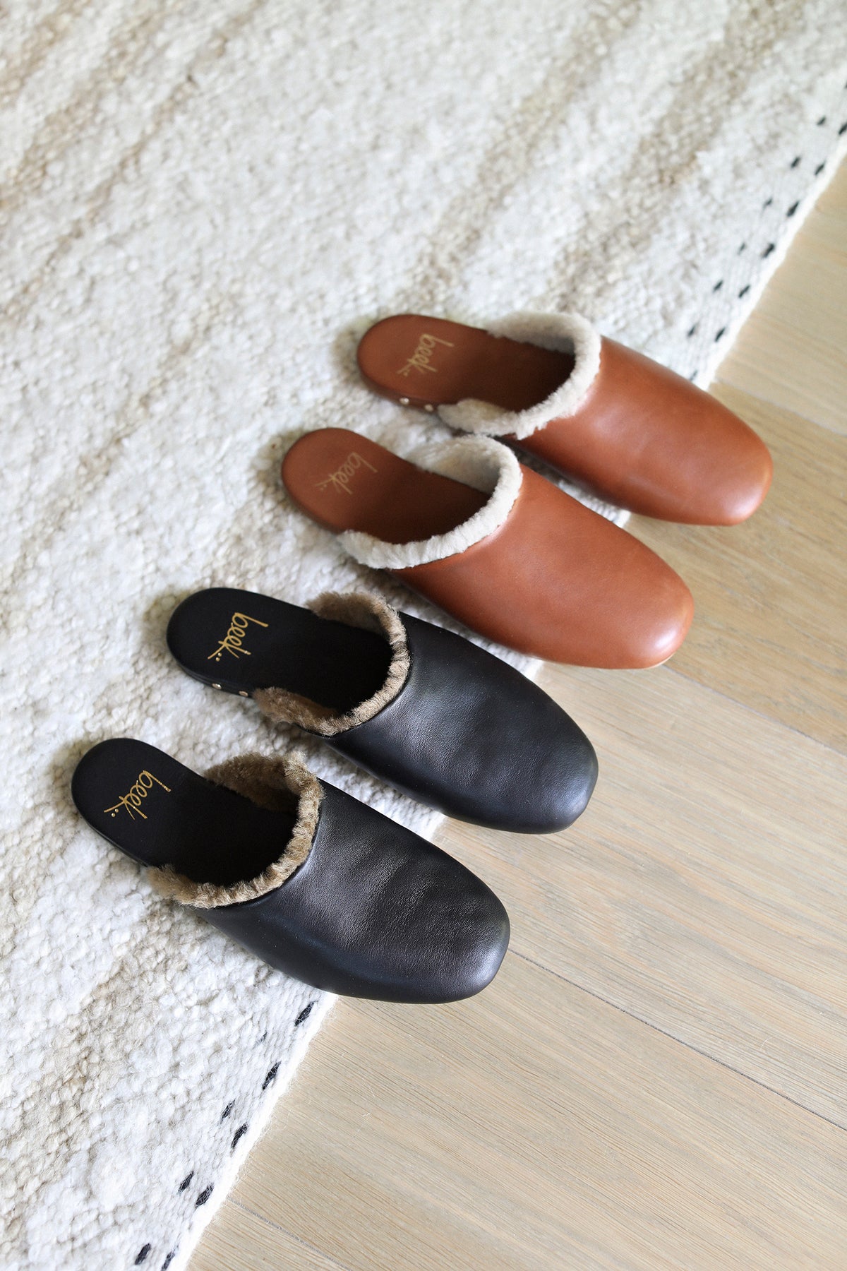 Group shot of Blackbird Shearling leather mule in cognac and black on a rug