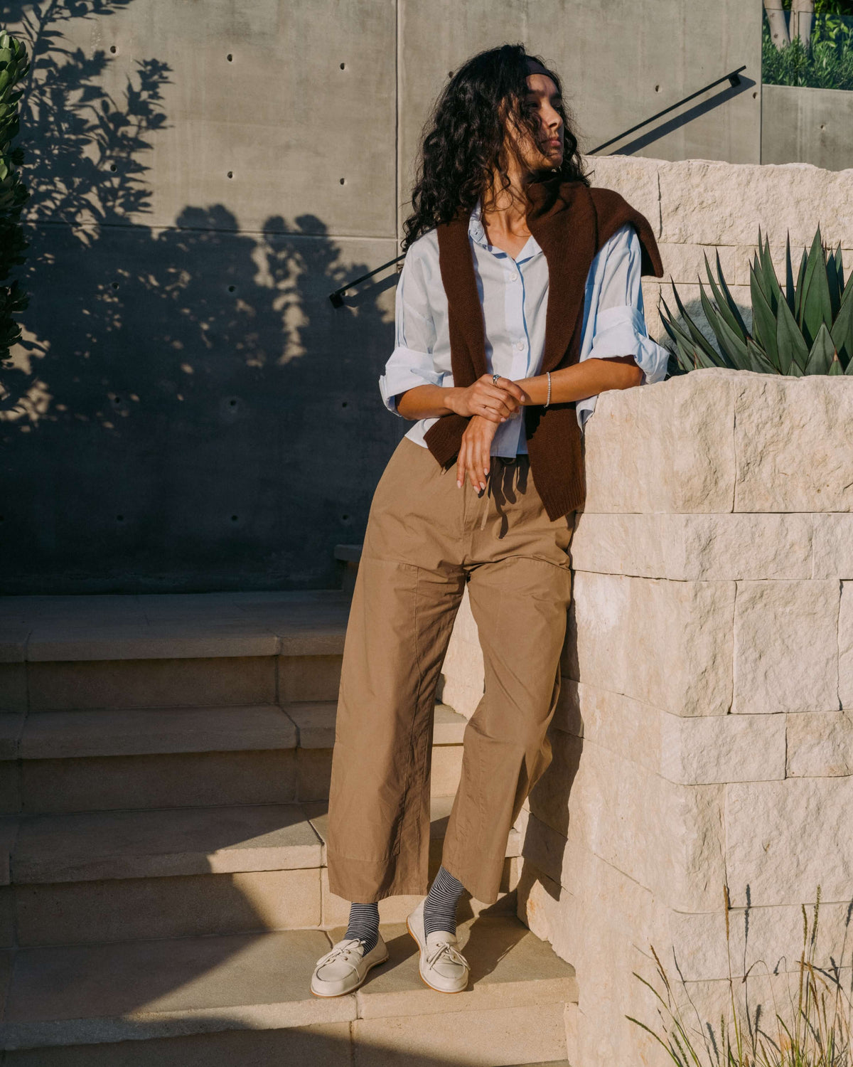 Woman wearing Boatbird leather loafers in vanilla with striped socks, beige pants, blue shirt
