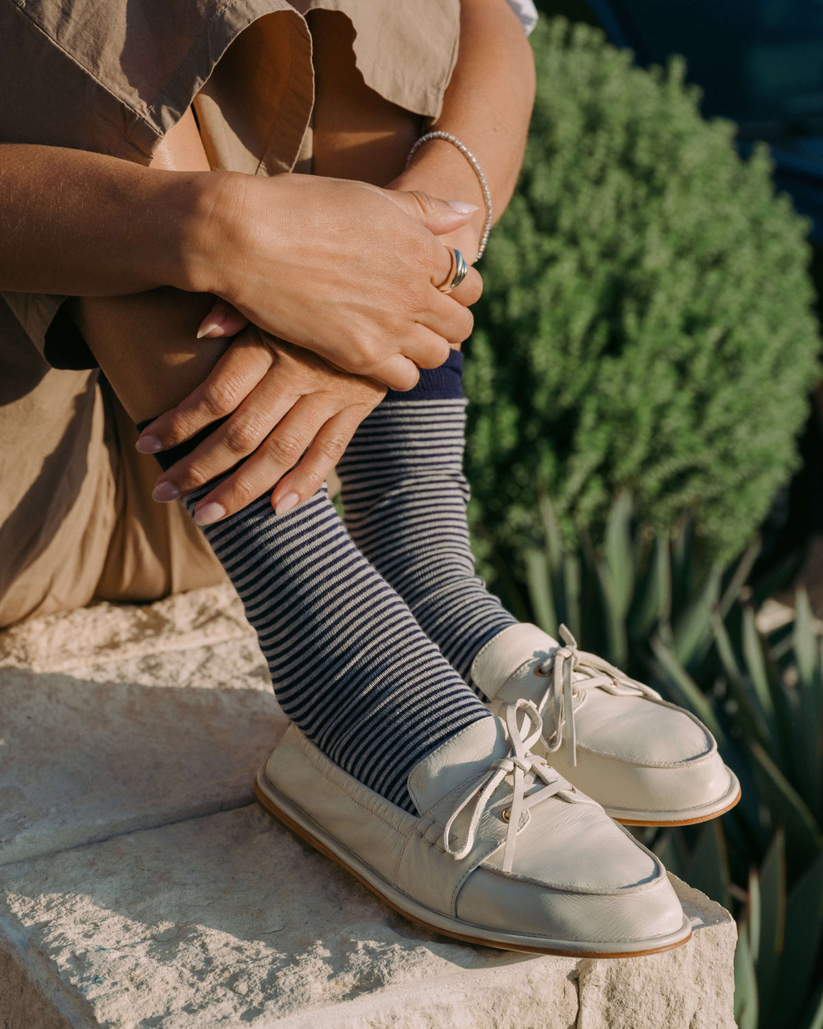 Woman wearing Boatbird leather loafers in vanilla with striped socks, beige pants