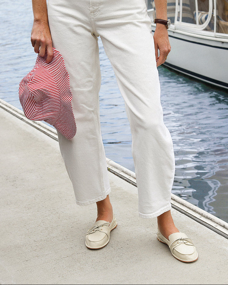 Woman wearing Boatbird leather loafers in vanilla with white pants and sweater on a dock