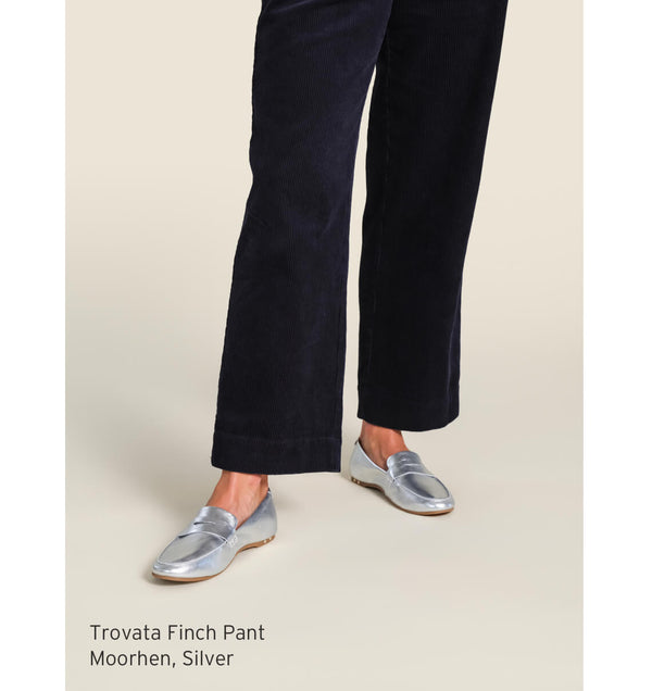Woman wearing Trovata Finch pant with beek Moorhen leather loafers in silver.