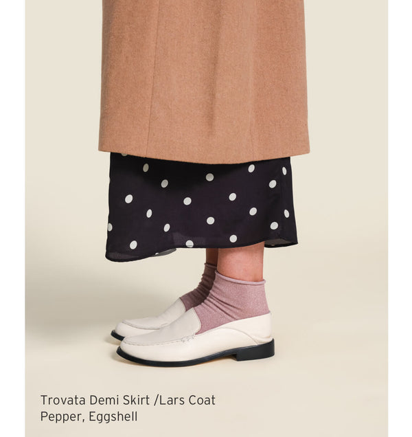 Woman wearing Trovata Demi skirt and Lars coat with beek Pepper leather loafers in eggshell.