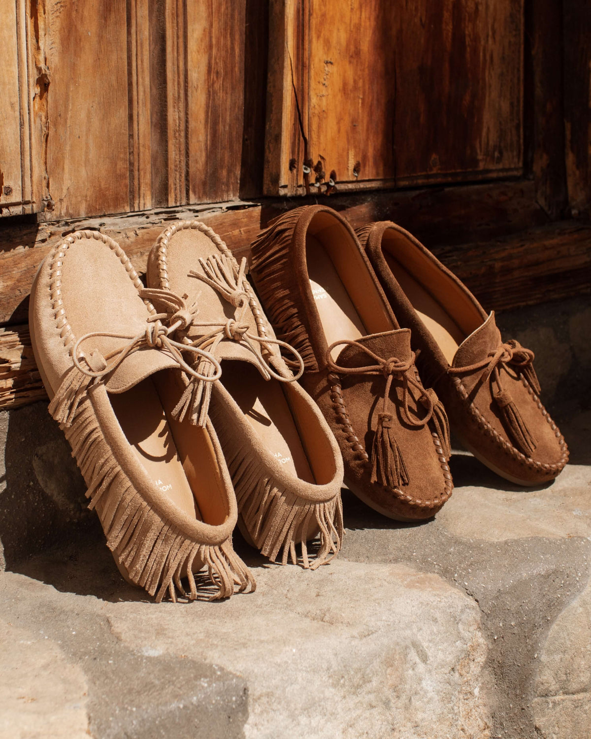 Group shot of Burke suede moccasin shoe in oat and chestnut propped up against wall