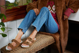 Woman wearing Buzzard Shearling sandals in chestnut with jeans, sweater, and jacket.