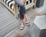 Woman wearing Calibird leather slide sandals in eggshell/black with grey jeans