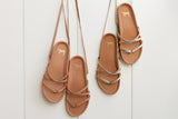 Canary leather ankle-tie sandals in honey and gold/honey hanging on a wall.